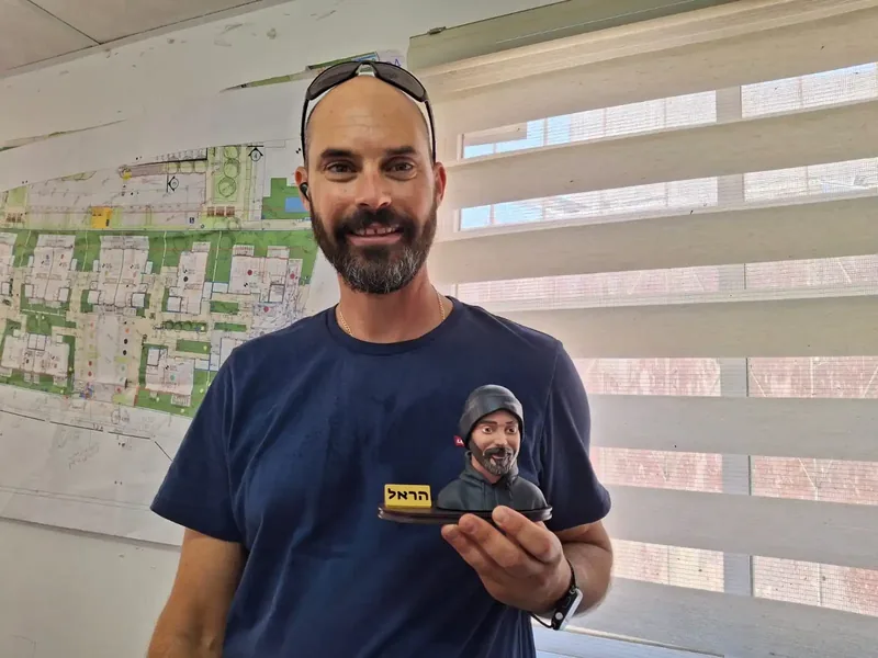 אדם מחזיק פסלון פורטרט קטן בכף ידו
